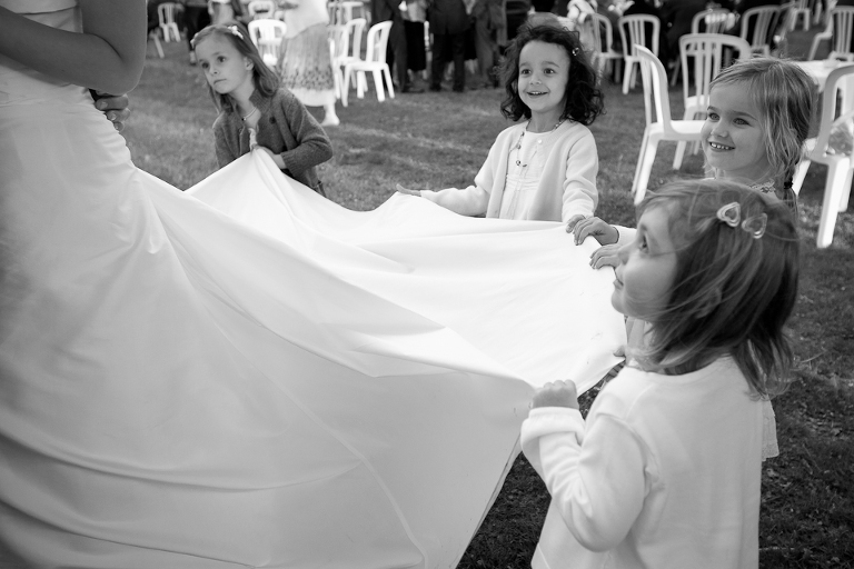 Demoiselles d'honneur tenant la robe de la mariée en souriant