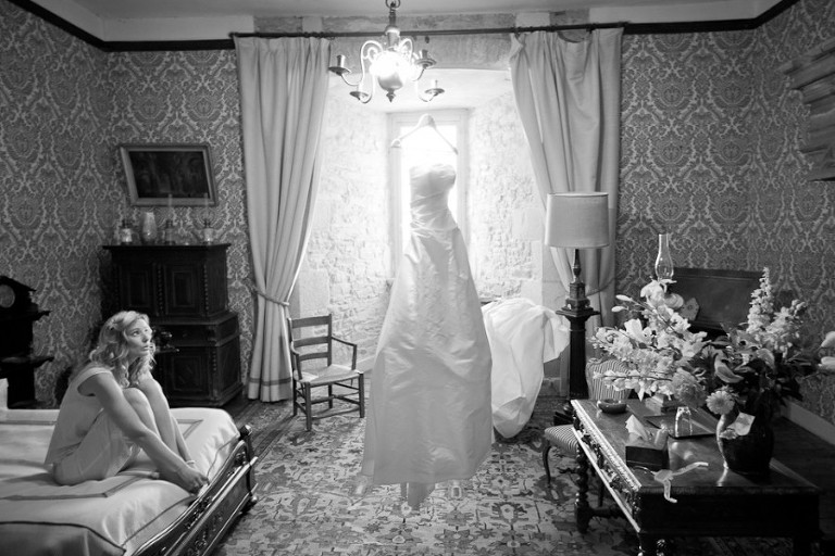 Mariée regardant sa robe accrochée à un cintre