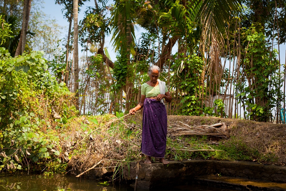 Vieille dame pêchant avec une canne en bois dans les backwaters du Kerala